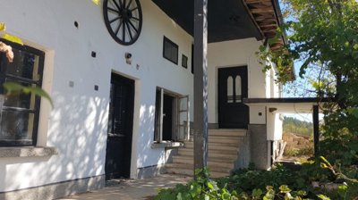 White exterior wall of the house featuring black doors, windows, and a decorative wooden wagon wheel