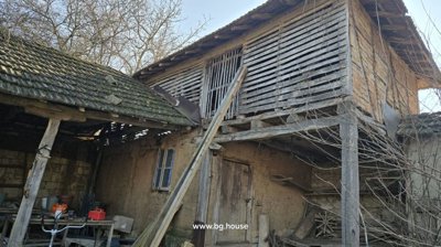 Old wooden barn with slatted upper walls and wooden door supported by angled wooden beams