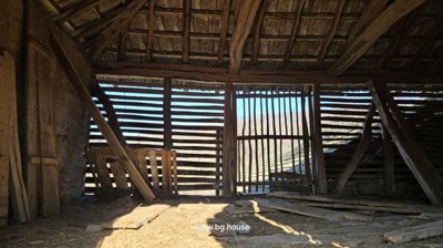 Inside view of a wooden barn showing slatted walls and wooden roof structure