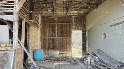 Interior view of a wooden barn showing an open door and scattered items on the floor