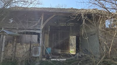 Exterior view of a wooden barn structure with an open entrance and brick wall inside