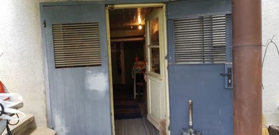 Entrance to a basement or storage area with open metal and wooden doors showing a table and light bulb inside.