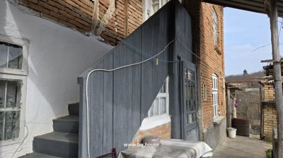Exterior of a brick house showing a wooden staircase and door with clotheslines overhead.