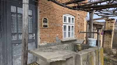 Concrete outdoor sink with faucet and mortar and pestle, next to a brick house wall with windows and door.