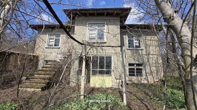 View of the two-storey house with external stairs and multiple windows, surrounded by leafless trees.
