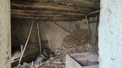Interior space featuring wooden beams supporting the ceiling and dried plant material scattered on the floor