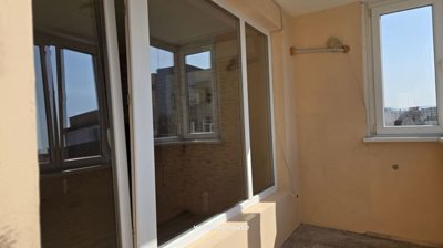 Corner view of enclosed balcony showing beige walls and white framed windows