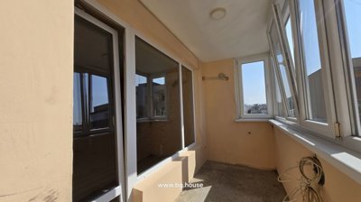 Wide view of enclosed balcony featuring beige walls and white framed windows