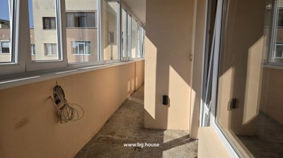 Enclosed balcony corridor with beige walls and white framed windows on one side