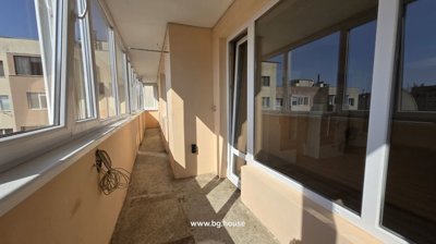 Long enclosed balcony corridor with beige walls and white framed windows