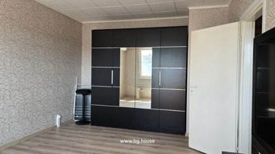 Living room featuring a large black wardrobe with a central mirror, a black stool, and a drying rack against patterned wallpaper.
