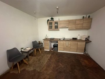 Interior kitchen featuring wooden cabinets, two gray chairs, and a small table
