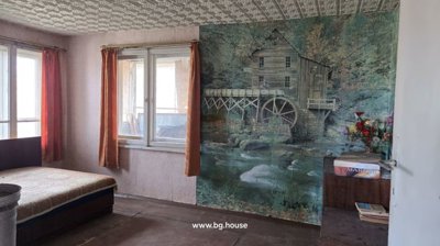 Bedroom featuring a bed, orange curtains, and a large mural depicting a watermill and river landscape on the wall.