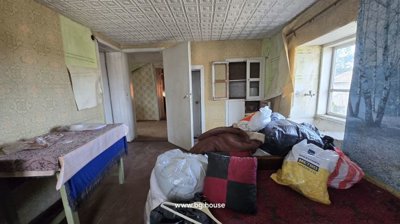 Interior room featuring a table covered with a cloth, a window, a door, and several bags piled on the floor.