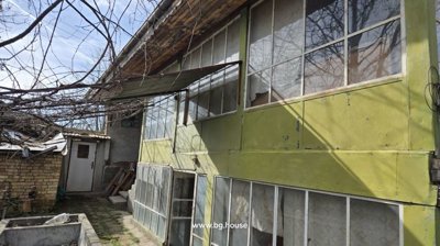 Side of a building featuring green painted panels and large windows, with an entrance door and yard area.