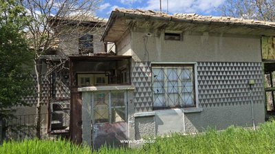 Detailed view of the house exterior highlighting patterned walls, windows, and a glass-enclosed porch