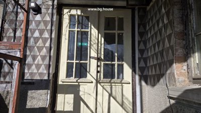 Close-up image of a wooden double door with multiple glass panes set in a patterned wall.