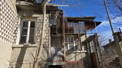 Side view of the house showing windows, patterned walls, and an enclosed porch with glass panels.