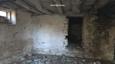 Interior view of a stone basement room featuring wooden ceiling beams and rough stone walls.
