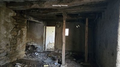 Interior of a basement room showing stone walls, wooden ceiling beams, and scattered debris on the floor.