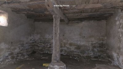 Interior view of a second basement room with stone walls, wooden beams, and a small window.