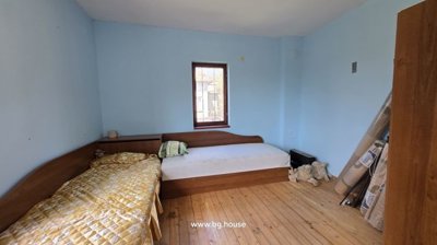 Bedroom featuring two single beds, wooden floor, and window with wooden frame