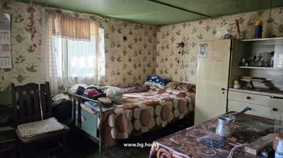 Interior view of a furnished bedroom featuring a bed, chair, table, and patterned wallpaper