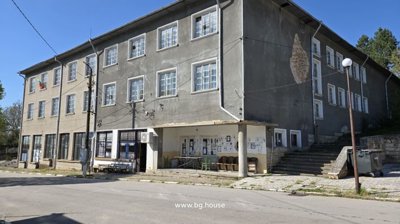 Front and side view of a three-storey commercial building with a covered porch and multiple windows in village Goritsa