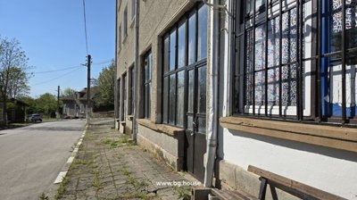 Side walkway along the commercial building showing barred windows and a bench near the entrance