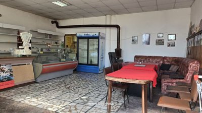 Interior room featuring tables with red cloths, chairs, a refrigerator, and display shelves