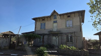 Front view of a two-storey Bulgarian house with textured walls and several windows.
