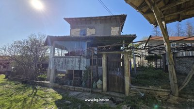 Two-storey house featuring a wooden balcony and fenced garden area under clear blue sky