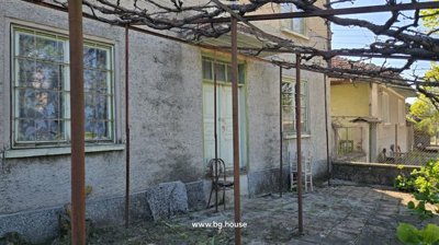 Side entrance of the house with an old wooden door and metal trellis overhead.