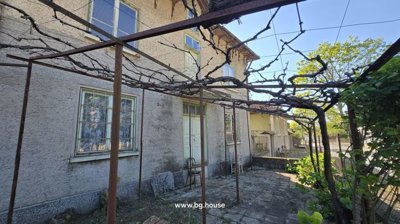 Side wall of the house featuring windows, a wooden door, and a metal trellis with bare vines.