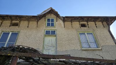 Close-up view of the upper floor windows and a small door with peeling paint.