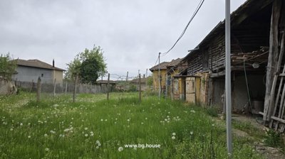 Garden space featuring grass, fence posts, and old wooden outbuildings along the side of the property.
