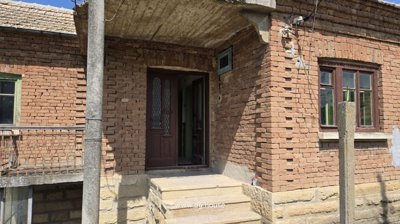 Entrance steps and wooden door under a concrete porch at the brick house in Gorsko Ablanovo