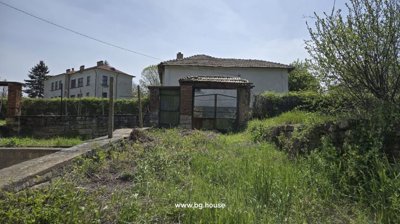 View of the garden gate, stone wall, and greenery near the Bulgarian house