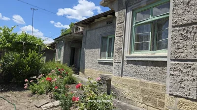 Close-up of the house exterior showing green window frames and a flower bed with red and pink flowers