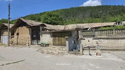 View of outbuildings and garage behind a stone fence, with village street and utility poles in the foreground.