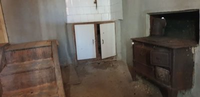 Interior room featuring plastered walls, a wood-burning stove, and a wooden bench along one wall.
