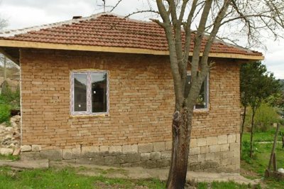 Side perspective of the rural house showing exposed brick walls and two newly installed windows.