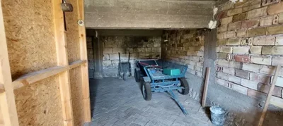 Storage area inside a brick building containing a garden cart and tools