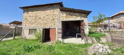 Rear view of an unfinished brick building with open garage doors and a grassy yard
