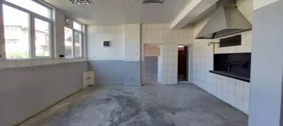 Interior of a bakery kitchen featuring tiled walls, a built-in oven, and a large ventilation hood