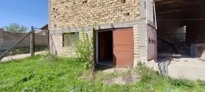 Open doorway leading to a storage room in a brick building with greenery outside