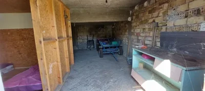 Interior of a storage room containing wooden shelving and various garden tools
