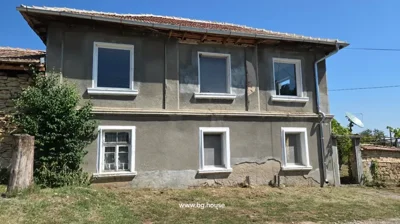 Two-story house with six windows, gray walls, and a metal downspout on the corner