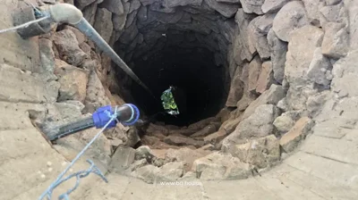 A stone-lined well with a pipe running inside it, visible from above.