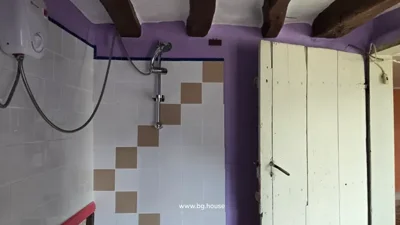 Shower area featuring a showerhead, tiled wall, and white door.